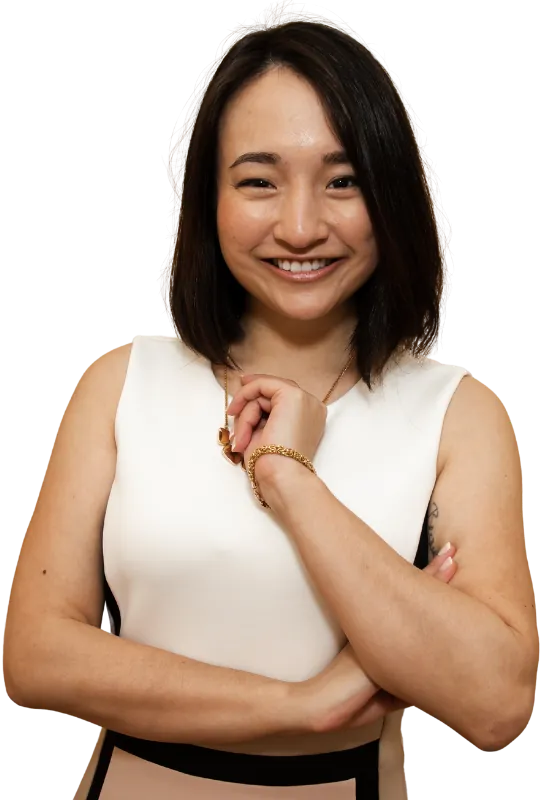 Joyce Akiko smiling with her arms crossed, in a white and blush dress